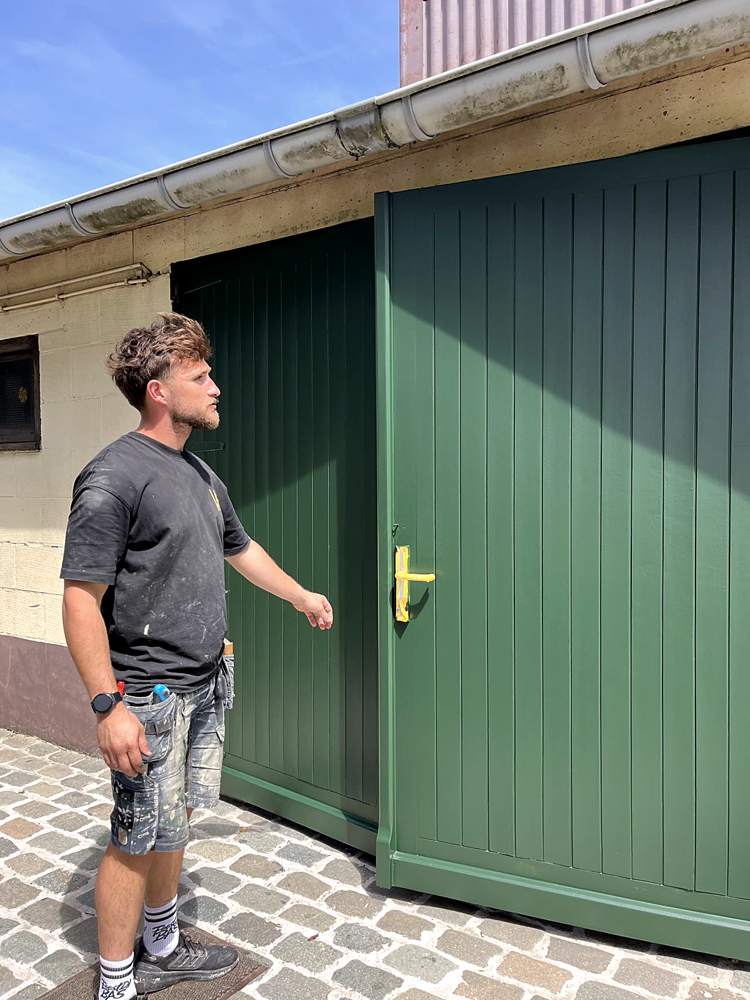 Schilder werkt een groene poort af in de zon