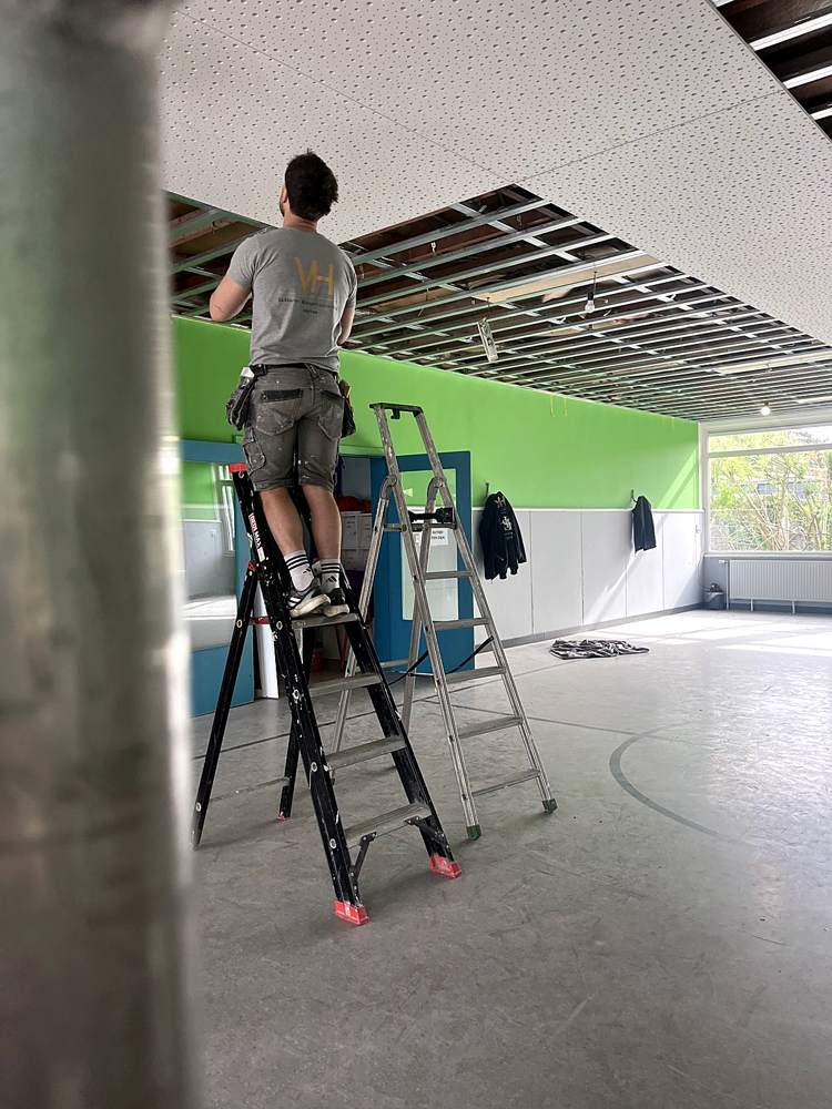 Monteur op ladder in sportzaal